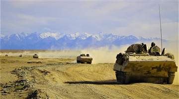 Armored vehicles march in formation during maneuver training